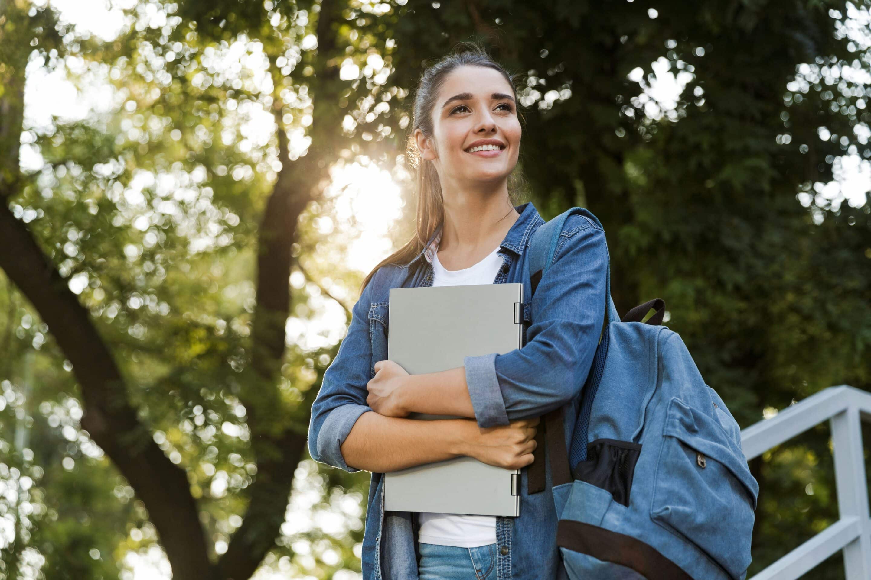 College student smiling after researching egg donation requirements on a laptop