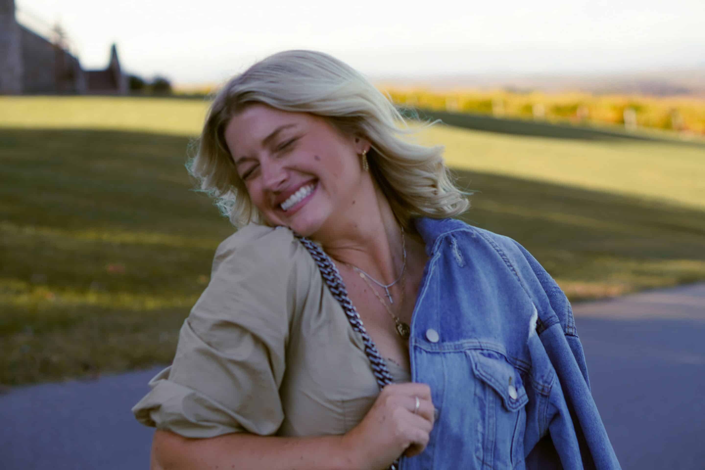 Smiling college-age woman who has donated eggs laughing outdoors in golden light